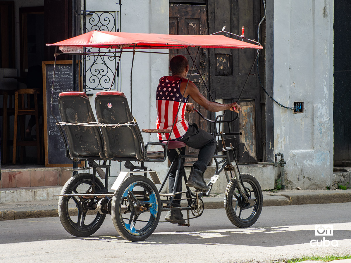 Chofer de bicitaxi con una camiseta con la bandera de Estados Unidos, en La Habana. Foto: Otmaro Rodríguez.