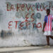 Un hombre con un pulóver de la bandera de EE.UU. pasa junto a un grafiti revolucionario en una calle de La Habana. Foto: Otmaro Rodríguez.
