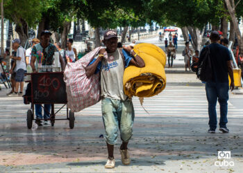 Un hombre carga bultos en el Paseo del Prado, en La Habana. Foto: Otmaro Rodríguez.