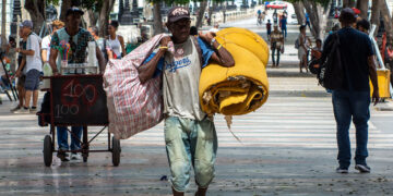 Un hombre carga bultos en el Paseo del Prado, en La Habana. Foto: Otmaro Rodríguez.