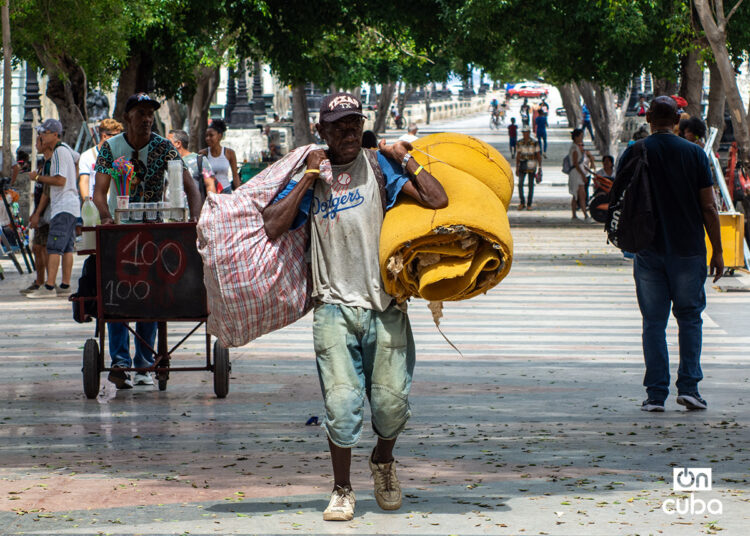 Un hombre carga bultos en el Paseo del Prado, en La Habana. Foto: Otmaro Rodríguez.