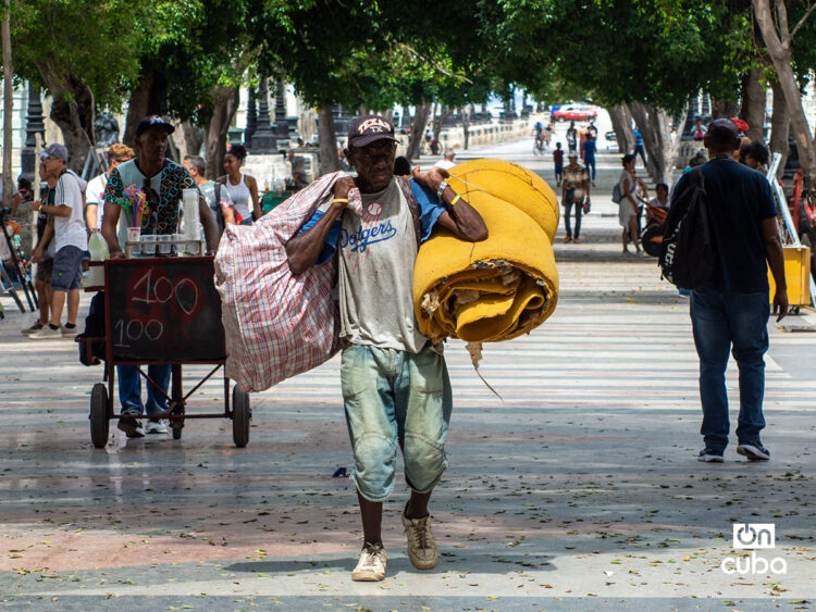 Un hombre carga bultos en el Paseo del Prado, en La Habana. Foto: Otmaro Rodríguez.