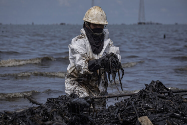 Fotografía del 29 de septiembre de 2026 de una empleada pública en una jornada de limpieza de petróleo derramado en una orilla del lago de Maracaibo. Foto: EFE/ Henry Chirinos.