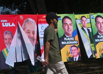 Un hombre camina frente a una tienda informal de banderas con la imagen del presidente de Brasil y candidato a la reelección, Luiz Inácio Lula da Silva y del candidato presidencial, Flávio Bolsonaro. Foto: EFE/Andre Borges.