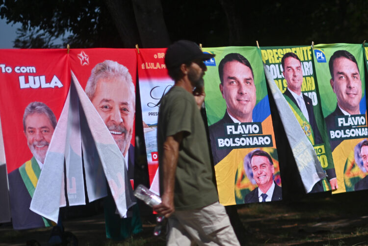 Un hombre camina frente a una tienda informal de banderas con la imagen del presidente de Brasil y candidato a la reelección, Luiz Inácio Lula da Silva y del candidato presidencial, Flávio Bolsonaro. Foto: EFE/Andre Borges.