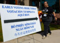 Una mujer camina junto a un cartel informativo durante la jornada de votación anticipada el lunes 19 de octubre en Houston, Texas. Foto: EFE/ Carlos Ramírez.