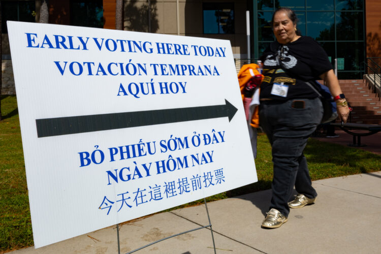 Una mujer camina junto a un cartel informativo durante la jornada de votación anticipada el lunes 19 de octubre en Houston, Texas. Foto: EFE/ Carlos Ramírez.