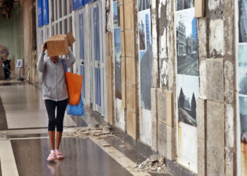 Una mujer se protege de la lluvia durante un frente frío en La Habana. Foto: Ernesto Mastrascusa / EFE / Archivo.