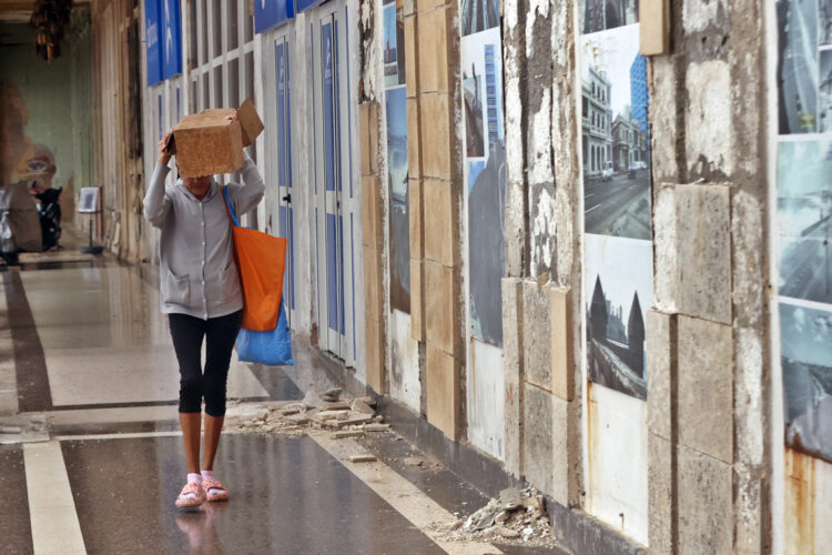 Una mujer se protege de la lluvia durante un frente frío en La Habana. Foto: Ernesto Mastrascusa / EFE / Archivo.