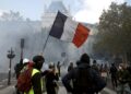 Manifestantes sostienen una bandera francesa mientras participan en una protesta contra el aumento del costo de vida y los recortes en los servicios públicos en la plaza de la República, en París, el 17 de octubre de 2026. Foto: EFE/EPA/MOHAMMED BADRA.