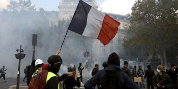 Manifestantes sostienen una bandera francesa mientras participan en una protesta contra el aumento del costo de vida y los recortes en los servicios públicos en la plaza de la República, en París, el 17 de octubre de 2026. Foto: EFE/EPA/MOHAMMED BADRA.