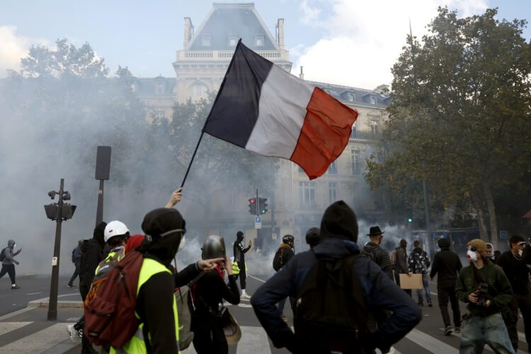 Manifestantes sostienen una bandera francesa mientras participan en una protesta contra el aumento del costo de vida y los recortes en los servicios públicos en la plaza de la República, en París, el 17 de octubre de 2026. Foto: EFE/EPA/MOHAMMED BADRA.